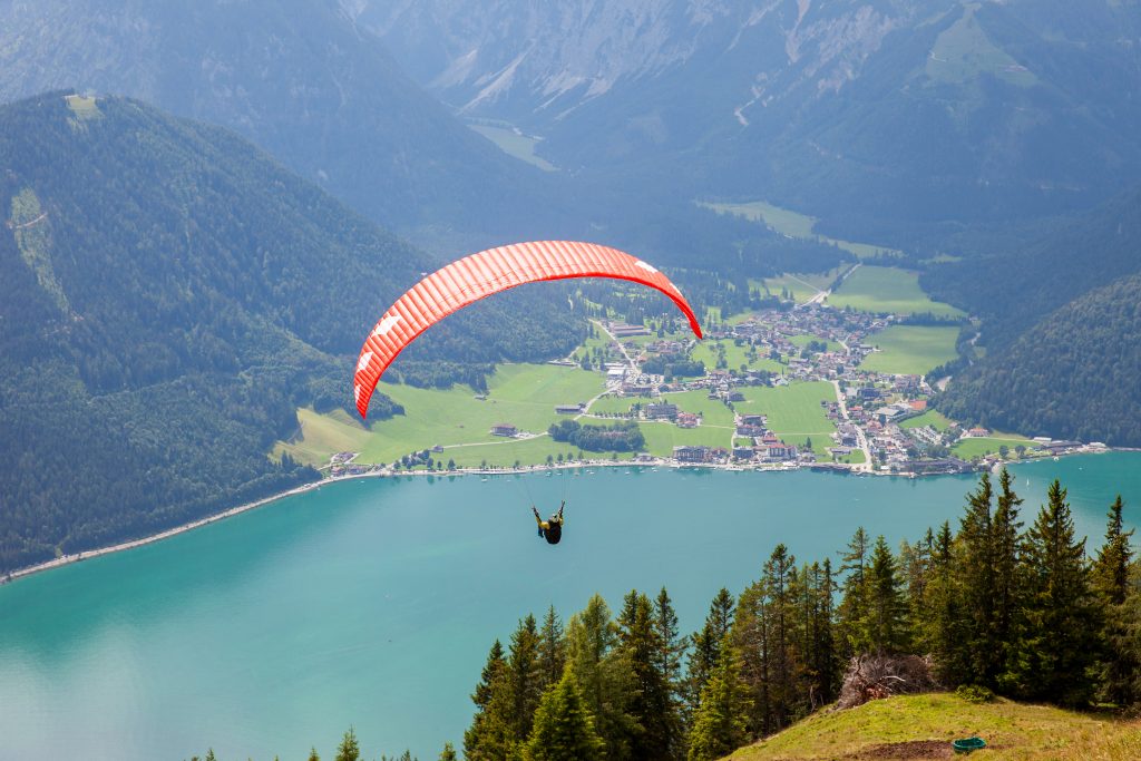 Ein Paragleiter schwebt hoch über dem Achensee. © ServusTV - DMG