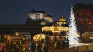 Vista della fortezza di Kufstein illuminata con decorazioni natalizie e un mercatino di Natale in primo piano.