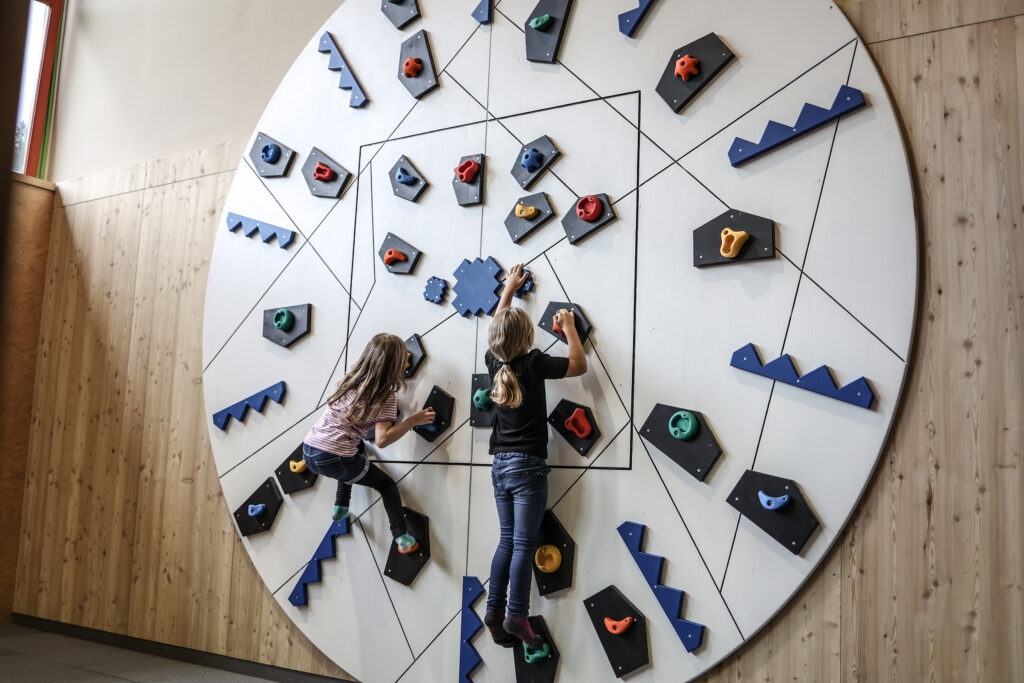 Der Indoor-Holzspielplatz mit Boulderwand bietet Kindern auch bei Schlechtwetter Raum zum Klettern, Ausprobieren und Austoben.