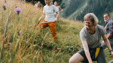 Teilnehmer eines Alm-Kurses beim traditionellen Sensenmähen – Inmitten der Berglandschaft des Bergsteigerdorfs St. Jodok, Schmirn- und Valsertal vermittelt die Schule der Alm praktische Fertigkeiten der alpinen Landwirtschaft.