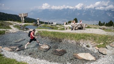 Mann springt über Steine im Zirbensee