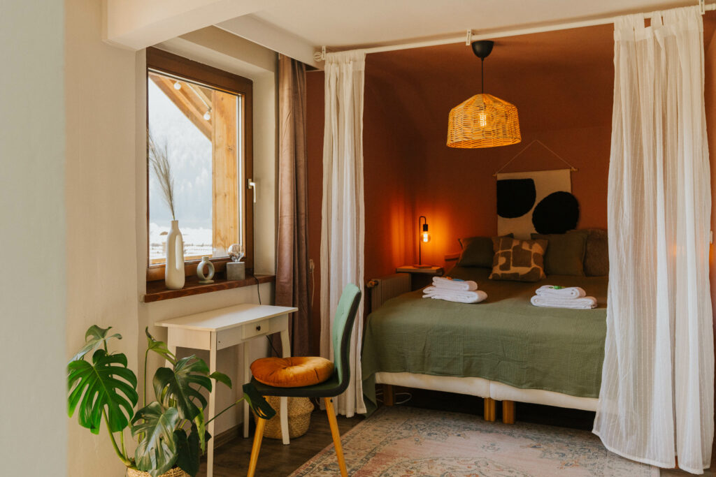 Eines der individuell gestalteten Zimmer im Wienerhof: Warme Farben, natürliche Materialien und Bergblick schaffen eine ruhige Umgebung für Rückzug, Erholung oder fokussiertes Arbeiten.